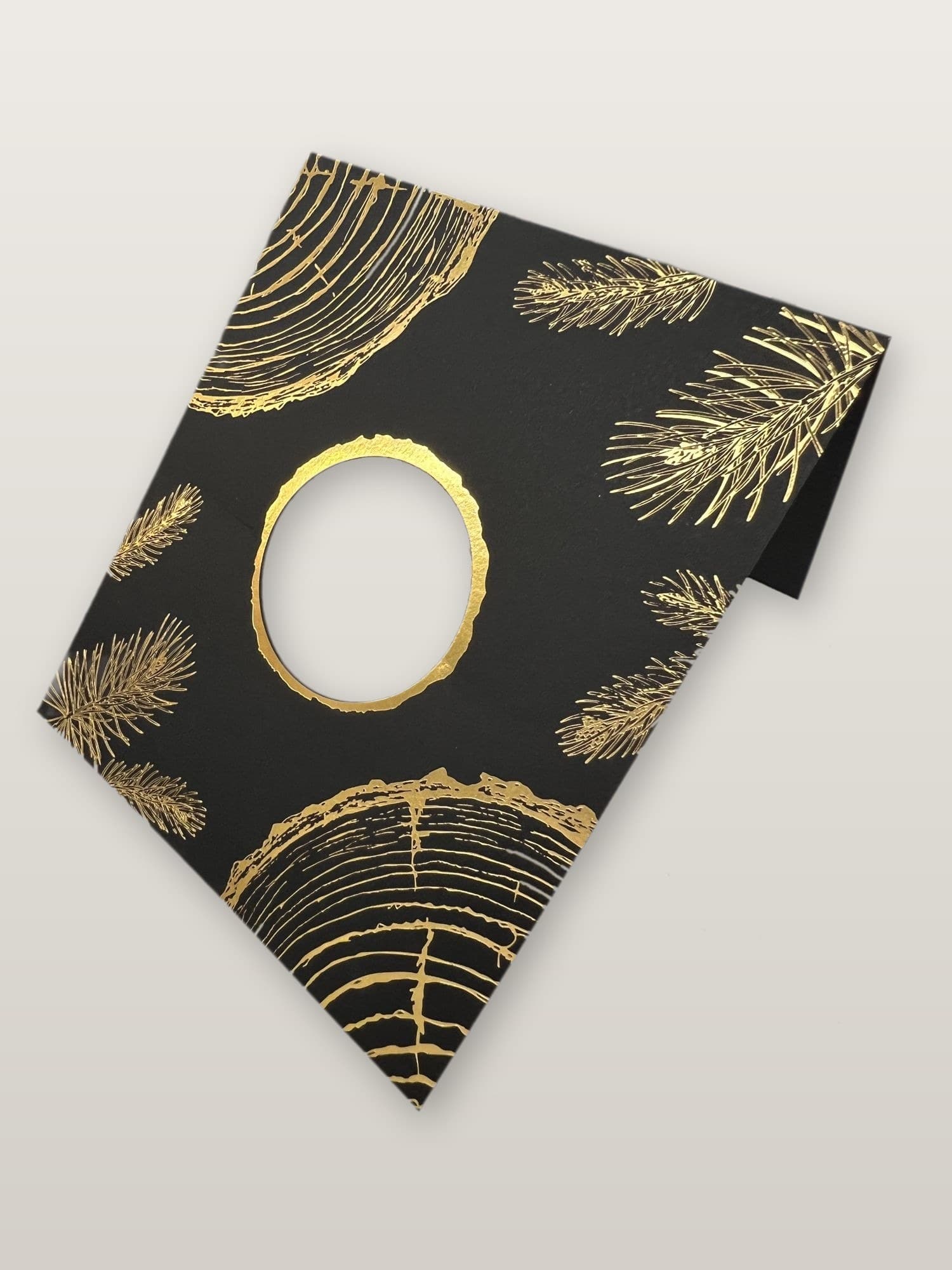 A die-cut circular opening with a gold foil-stamped edge on black stock